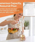 Person pouring drink from 2 Quart Glass Pitcher With Filter Lid Airtight Leakproof 64 Oz Cold Water Jug For Lemonade Tea Juice Milk Iced Coffee And Fruit Drinks Crystal Glass With BPA Free Lid Great For Home Kitchen No Spill Design