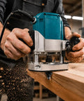 Hands using Heavy Duty 12 Piece Tungsten Carbide Router Bits Set With Standard Quarter Inch Shank on a wooden surface.