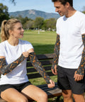 Cooling Arm Sleeves With Upf Fifty Plus Uv Blocking And Breathable Moisture Wicking Material For Running Cycling And Yard Work Flexible Compression Guards That Keep You Fresh On The Daily Grind worn by two people in a park.