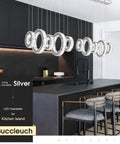 Five Ring Crystal Chandelier Pendant Light With Height Adjustable Stainless Steel Frame Dope K9 Crystals UL Certified Dimmable LED 6000K 4400lm For Dining Room Living Room Bedroom, hanging over modern kitchen island with stools.