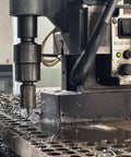 Front view of Euroboor magnetic drill press drilling metal; chips on worktable and control panel visible.