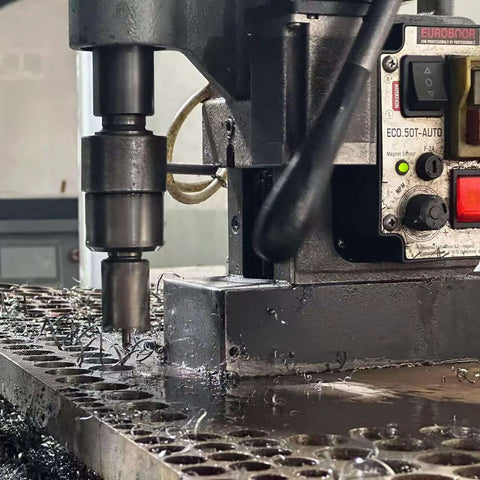 Front view of Euroboor magnetic drill press drilling metal; chips on worktable and control panel visible.