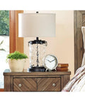 Glass Table Lamp With Bronze Finish Base And Fabric Drum Shade on a wooden nightstand in bedroom decor.