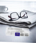 Image of eyeglasses on a stack of newspapers with an Eyeglass Repair Tools Kit With Screws Nose Pads And Tiny Screwdriver in the foreground.