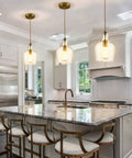 Lit Brushed Gold Pendant Light With Clear Glass Shade, Adjustable 59 Inch Cord in modern kitchen island setting