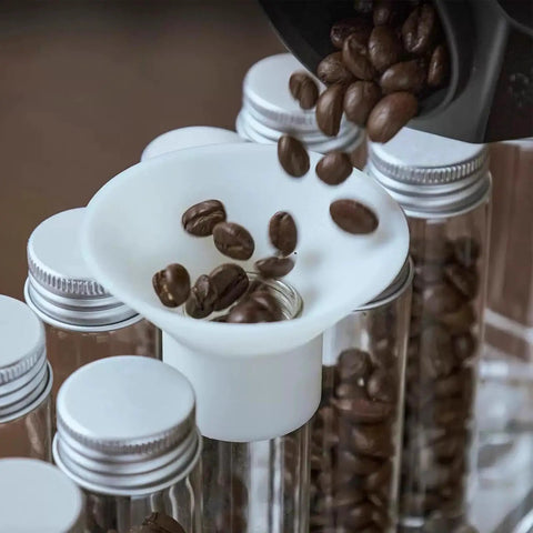 14 Piece Airtight Glass Coffee Bean Storage Tubes With Solid Stand And Hopper Featuring One Way Exhaust Valve Keeps Your Daily Grind Pretty Slick For That Weekend Home Bar Session Countertop Flex with coffee beans being poured