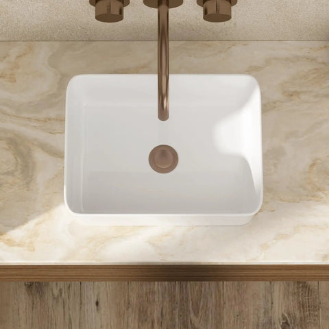 Rectangular white ceramic basin on marble counter with bronze faucet