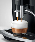 NoDrama Automatic Coffee Machine With OneTouch Espresso Brewing Milk Froth And Rapid SelfClean Design Programmable Strength Volume Controls For Smooth Daily Grinds In Piano Black brewing espresso in a glass cup with milk froth.