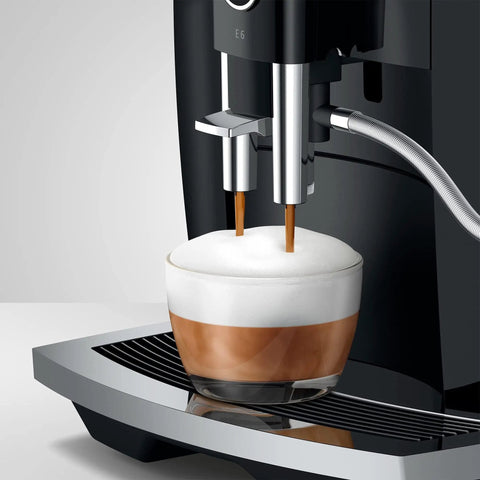 NoDrama Automatic Coffee Machine With OneTouch Espresso Brewing Milk Froth And Rapid SelfClean Design Programmable Strength Volume Controls For Smooth Daily Grinds In Piano Black brewing espresso in a glass cup with milk froth.