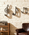 3 Piece Music Note Cast Iron Wall Hooks For Hanging Your Coats Hats And Totes Pretty Sweet Decorative Heavy Duty Coat Rack mounted on a white brick wall.