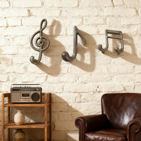 3 Piece Music Note Cast Iron Wall Hooks For Hanging Your Coats Hats And Totes Pretty Sweet Decorative Heavy Duty Coat Rack mounted on a white brick wall.