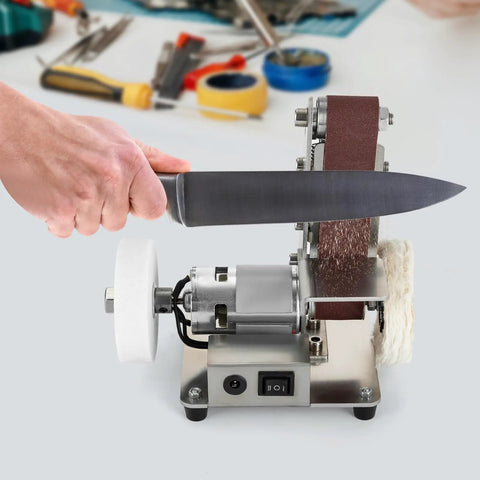 Mini Bench Belt Sander Featuring Slick Adjustable Speed Controls Built Tough As Nails From Stainless Steel Includes Twenty Top Shelf Abrasive Belts To Crush Wood Metal And Knife Polishing Projects Around The Private Garage, with knife being sharpened.