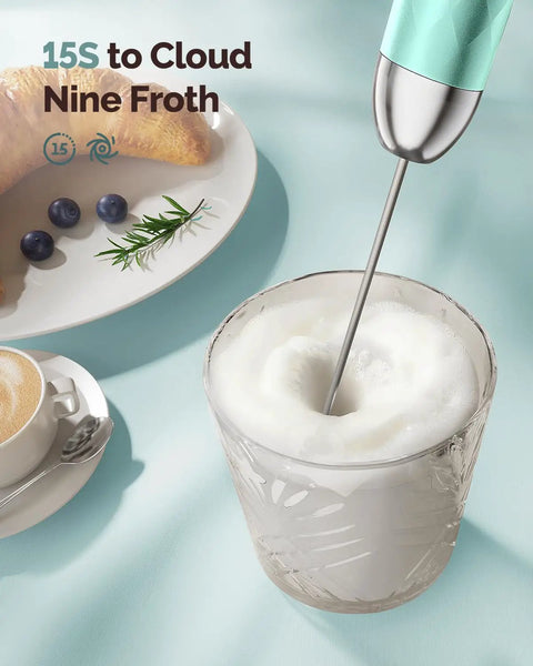 Rechargeable Milk Frother Handheld Wand With Stepless Speed Control and 3 Whisks frothing milk in a glass, Gulf Blue, close-up.