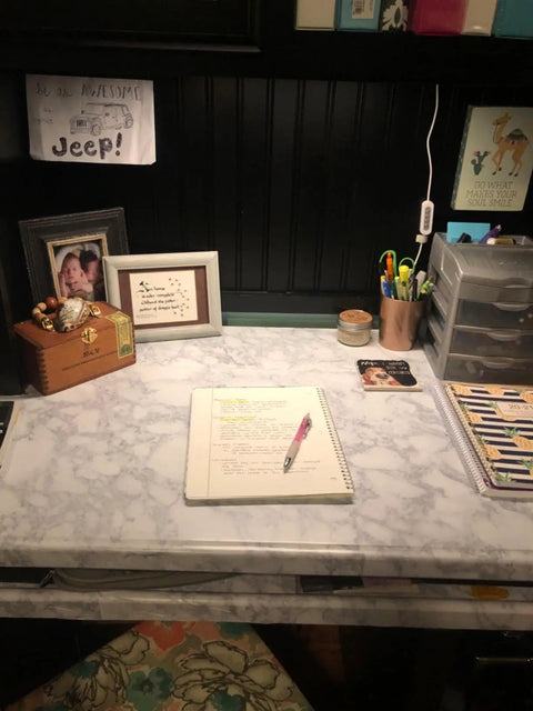 Organized desk setup with marble-look surface, notebook, pens, and decor elements; ideal for under desk lighting installation.