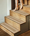 Person walking on wooden stairs with 15 Pack Non Slip Stair Treads 8x30 Inches For Indoor Wooden Stairs Beige Reusable Machine Washable Carpet