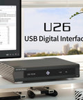 U26 USB Digital Interface DDC With DSD2048 And PCM1.536MHz OCXO For Ultra Clean Audio USB And 10MHz Clock Input Dual IIS AES Optical And BNC Outputs Low Noise Digital Bridge For X30 R30 on a desk with controllers.