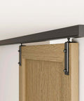 6.6 Foot Ceiling Mount Box Rail Barn Door Hardware Kit installed with wooden door, showing black powder-coated finish and nylon rail hangers.