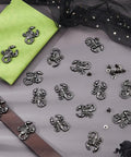 Badass Gunmetal Scorpion Screw Back Studs 16 Sets arranged on gray surface with green notebook and brown belt.