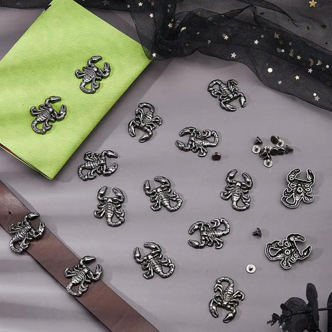 Badass Gunmetal Scorpion Screw Back Studs 16 Sets arranged on gray surface with green notebook and brown belt.