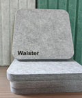 Snag This 4 Pack Of Polyester Fiber Acoustic Panels Self Adhesive Sound Proof Tiles 0.4 Inch Thick stacked gray felt tiles on wood.