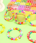 Colorful Fruit Polymer Clay Beads Bracelet Making Kit With Lemon Strawberry Avocado Watermelon Designs For DIY Jewelry Crafting Necklace And Bracelet Making Supplies displayed in a divided storage box on a green background with sample bracelets.