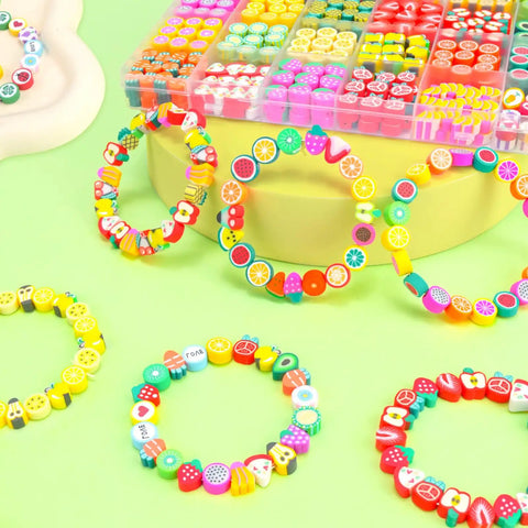 Colorful Fruit Polymer Clay Beads Bracelet Making Kit With Lemon Strawberry Avocado Watermelon Designs For DIY Jewelry Crafting Necklace And Bracelet Making Supplies displayed in a divided storage box on a green background with sample bracelets.