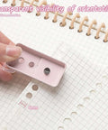 Hand using 2 Pack Mini Hole Punch 6mm Circle Holes Ultra Compact 10 Sheet Capacity Pocket Sized Puncher on notebook page