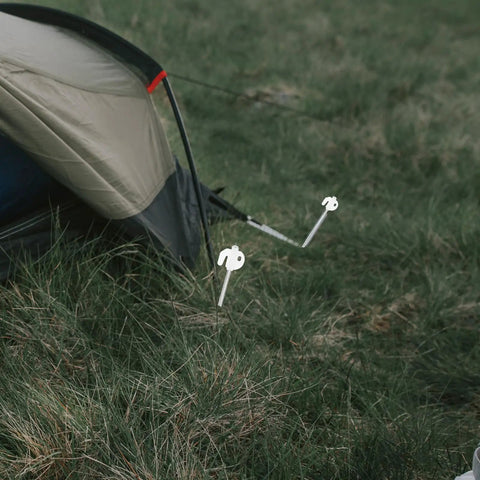 Heavy Duty Tent Stakes Set with Fluorescent Ground Pegs and Dark Cord securing a tent on grassy ground