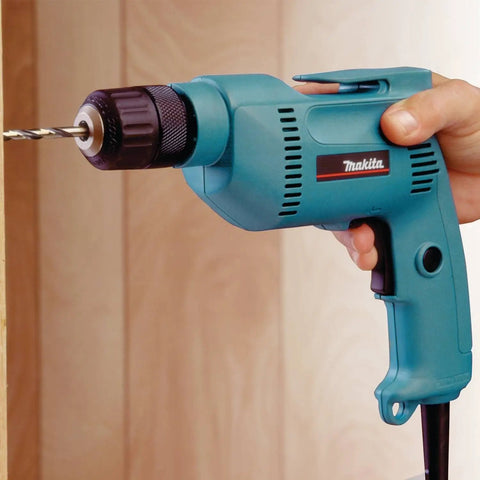 Hand using powerful 4.9 Amp 3/8 Inch Drill with variable speed 0-2500 RPM, keyless chuck, teal finish, drilling wood