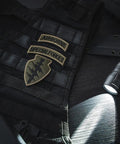 LH1 LED White Light Head Single Mode Throwing Beam for Outdoor Use next to tactical vest with patches in dim setting.