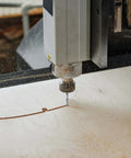 Spiral router bit, 1/4 inch carbide end mill installed on CNC router cutting wood (close-up)