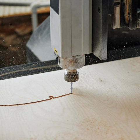 Spiral router bit, 1/4 inch carbide end mill installed on CNC router cutting wood (close-up)