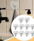 Heavy Duty Adhesive Wall Hooks With Slick Grip Keep Your Towels And Gear Locked In Place Zero Drilling Hassle Clear Transparent Look Fits Any Room Flawlessly, showing gray towel hung on heart-shaped hook.