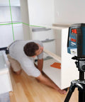 Green Beam Self-Leveling Cross-Line Laser Kit with 40 Ft Range in use for cabinet installation, showing green lines on the wall.