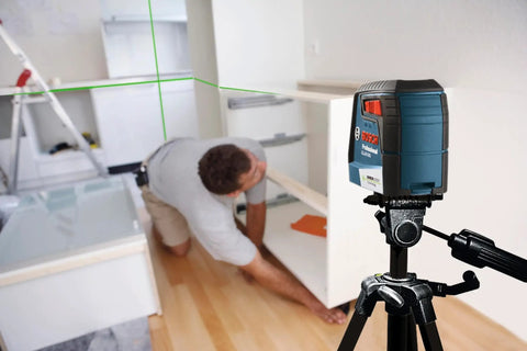 Green Beam Self-Leveling Cross-Line Laser Kit with 40 Ft Range in use for cabinet installation, showing green lines on the wall.