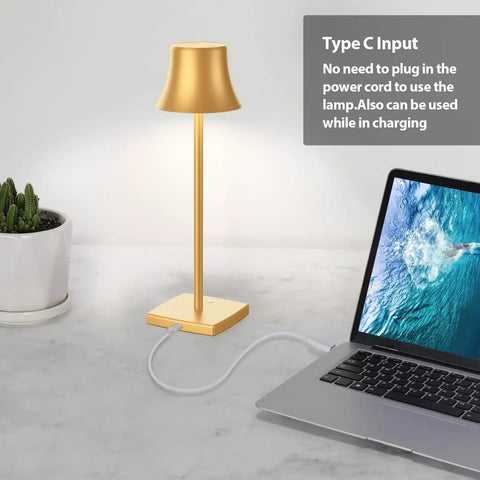 Cordless LED Desk Lamp On The Go with rechargeable 5000mAh battery next to a laptop, gold finish, USB-C cable connected