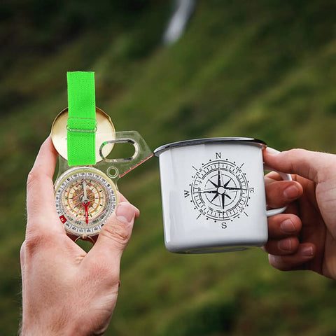 Thumb Type Precision Compass In Acrylic Pocket Tool For Hiking, Camping, And Orienteering held next to compass-themed mug