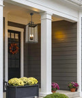 Large Twenty Five Inch Outdoor Pendant Light With Clear Glass And Sturdy Metal Build hanging above a porch with flowers.