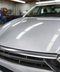 Automotive clear coat on a silver car hood in an auto repair shop