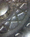 Close-up of Graphite Dry Lube for Wood Derby Cars with Tungsten Moly Boron Blend providing traction and lubrication on a metal surface.