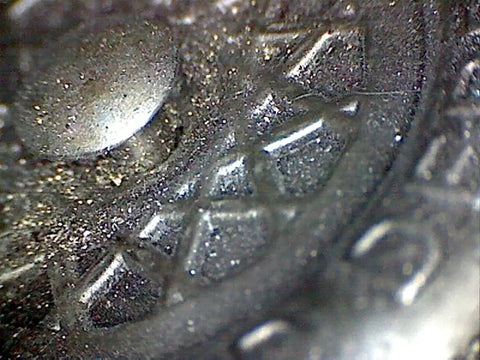 Close-up of Graphite Dry Lube for Wood Derby Cars with Tungsten Moly Boron Blend providing traction and lubrication on a metal surface.