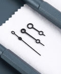 Black metal watch hands set for NH35 364R 7S movements on cloth, showing detailed horology repair accessories