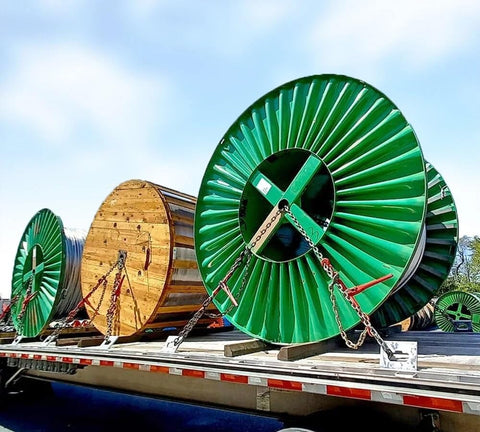 Four Pack Ratchet Chain Binders For 1/4 To 5/16 Inch G70 Chains securing cable reels on a flatbed trailer with forged steel construction.