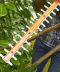 Heavy Duty Electric Hedge Trimmer With 420 Watt Motor And 45CM Cutting Blade For Fast Yard Cleanup cutting through a branch with orange blade.