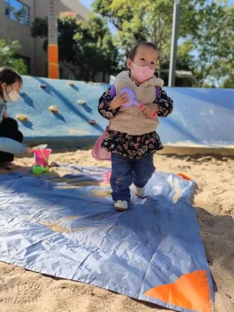 Child standing on Pocket Picnic Blanket For Grab And Go Outdoor Fun That Folds Small And Lightweight Sandproof 55 By 60 Inch Beach Mat