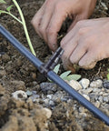 Hands installing 300 Piece Drip Irrigation Fittings Kit with Barbed Connectors for Garden Pots and Greenhouse in soil