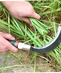 Close-up of a hand using a manganese steel sickle with ergonomic handle for cutting grass, part of a durable workhorse yard tool.