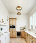 Gradient Gold Glass Pendant Light For Kitchen Island in modern kitchen, two globe fixtures with warm glow over countertops.