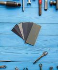 56 Piece Wet And Dry Sanding Sheets Kit With Assorted Grit 400 To 5000 for DIY projects, tools around on blue wooden table
