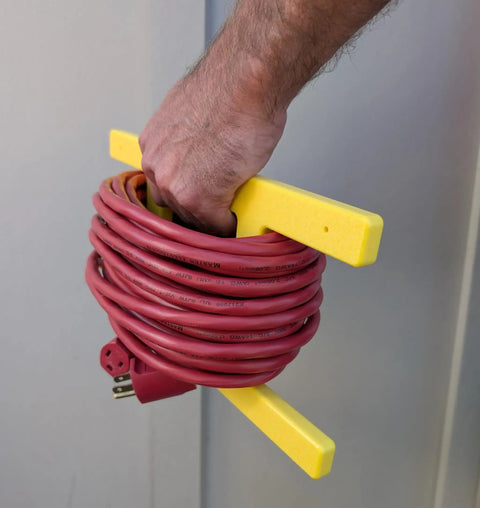 Hand holding heavy duty extension cord reel and yellow cord organizer set two pack that holds 100 feet each for quick wraps.